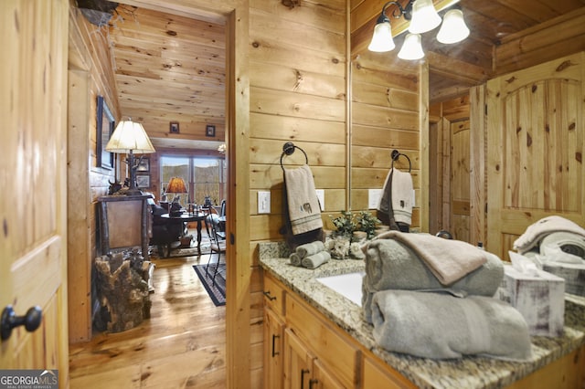 bathroom featuring wood walls, hardwood / wood-style floors, vanity, and wooden ceiling