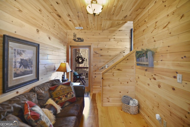 living area with wood-type flooring, wooden walls, and wooden ceiling