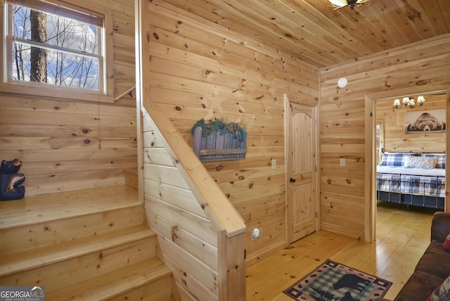 stairway featuring wood-type flooring, wooden ceiling, and wooden walls