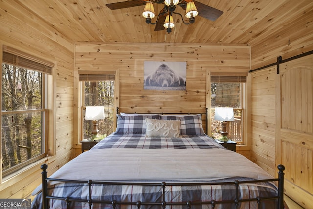 bedroom with wood walls, a barn door, and wood ceiling