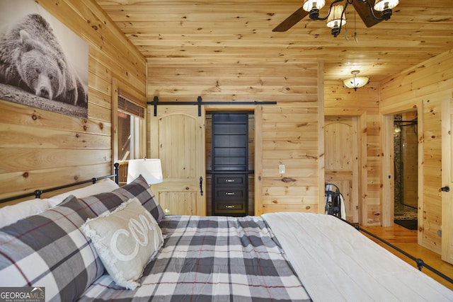 bedroom with a barn door, wood walls, and wooden ceiling