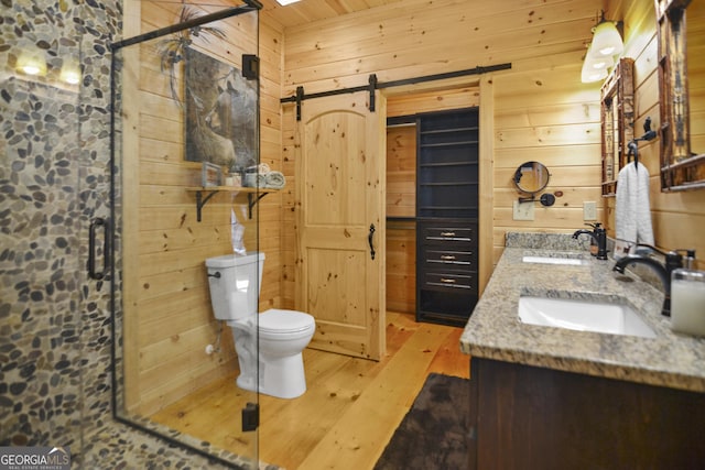 bathroom with an enclosed shower, vanity, wood-type flooring, toilet, and wood walls