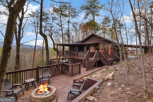 rear view of property with a deck with mountain view and a fire pit