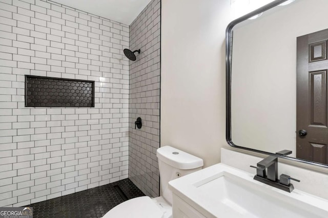 bathroom featuring toilet, vanity, and tiled shower