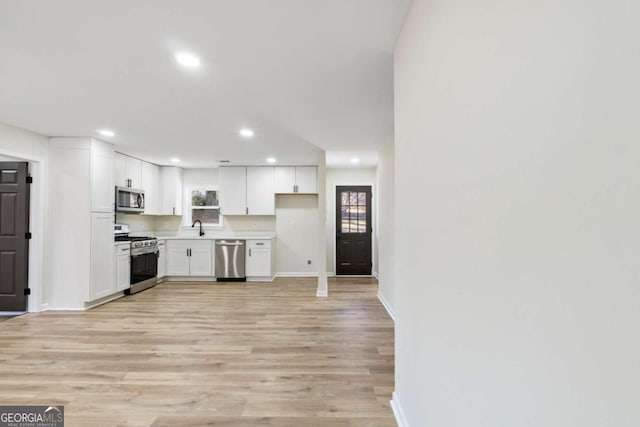 kitchen featuring sink, white cabinets, stainless steel appliances, and light hardwood / wood-style floors