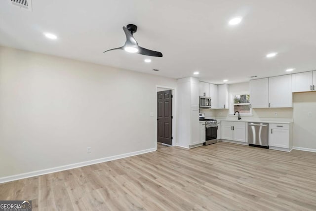 kitchen with white cabinets, stainless steel appliances, light hardwood / wood-style flooring, and sink