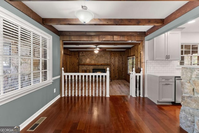 interior space featuring ceiling fan, a wealth of natural light, dark hardwood / wood-style floors, and beamed ceiling