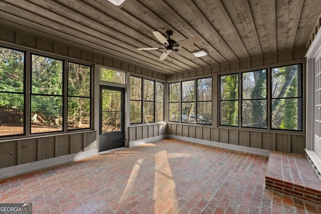 unfurnished sunroom with ceiling fan, plenty of natural light, and wood ceiling