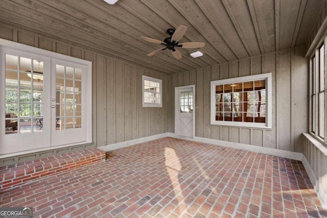 unfurnished sunroom featuring ceiling fan, a wealth of natural light, and wood ceiling