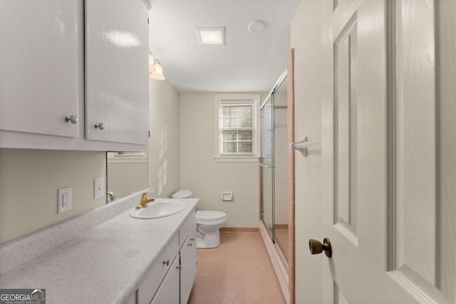 bathroom with toilet, vanity, and a shower with door