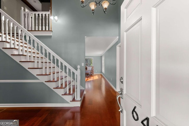 foyer featuring ornamental molding, wood-type flooring, and a notable chandelier