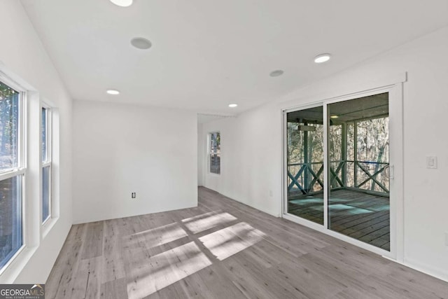 empty room with light hardwood / wood-style floors and plenty of natural light