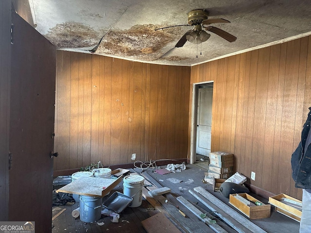 interior space featuring ceiling fan and wooden walls