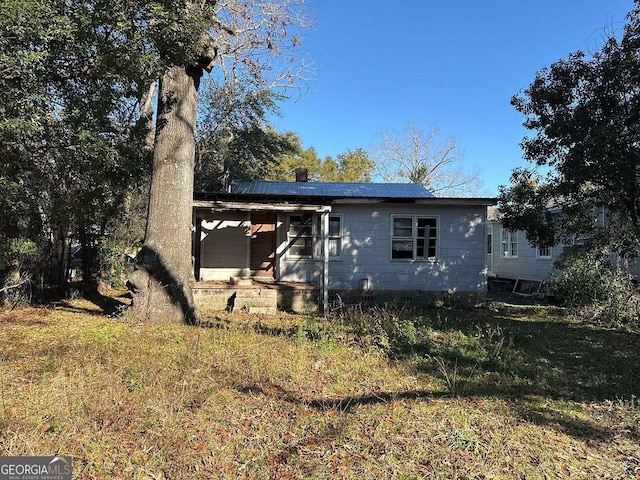 back of house with solar panels and a lawn