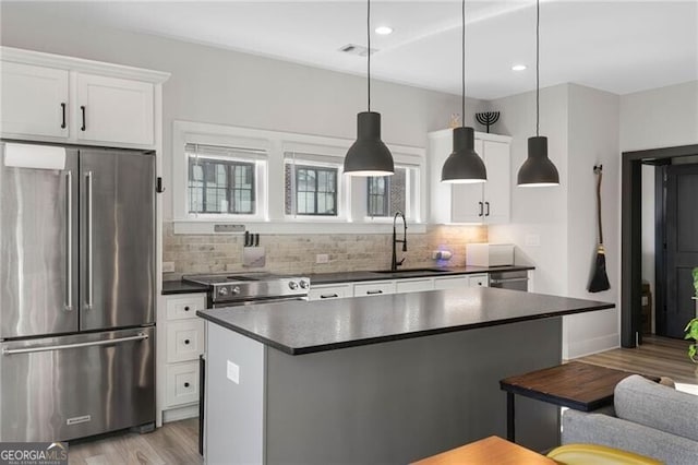 kitchen with sink, decorative light fixtures, white cabinetry, light wood-type flooring, and appliances with stainless steel finishes