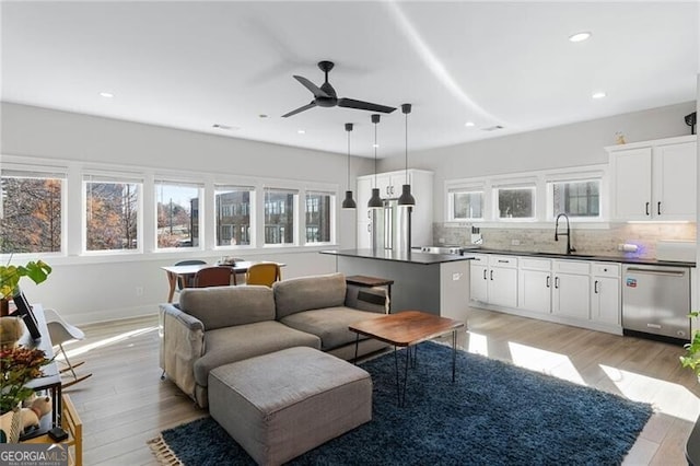 living room with sink, ceiling fan, and light wood-type flooring