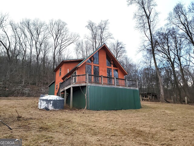 back of property featuring a wooden deck and a yard