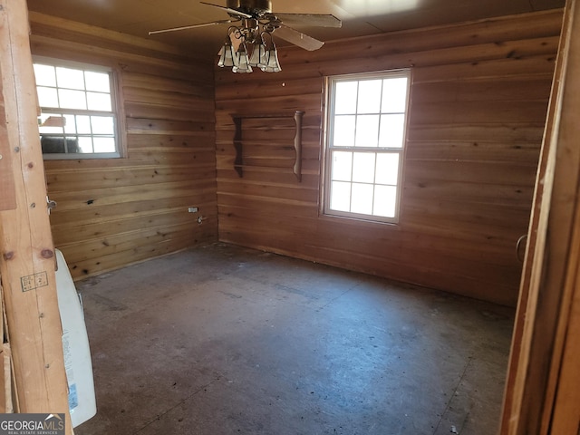 spare room with ceiling fan and wood walls