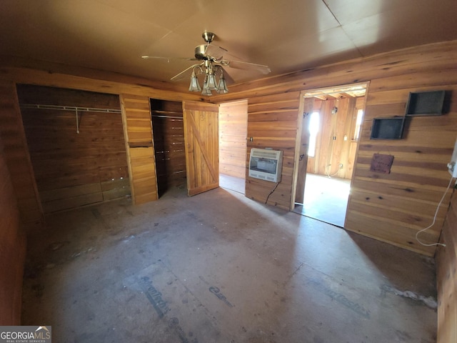 unfurnished living room featuring ceiling fan, concrete floors, heating unit, and wooden walls