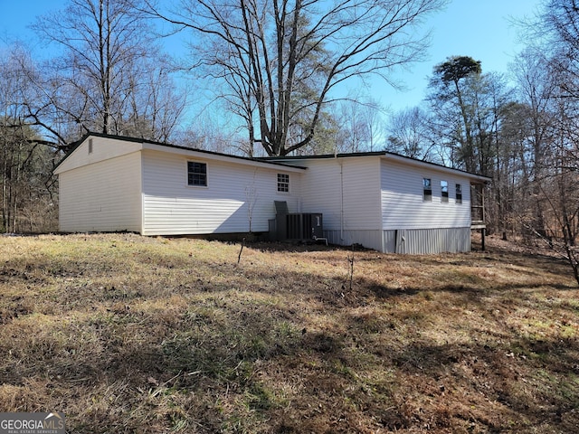 rear view of property featuring central AC unit and a yard