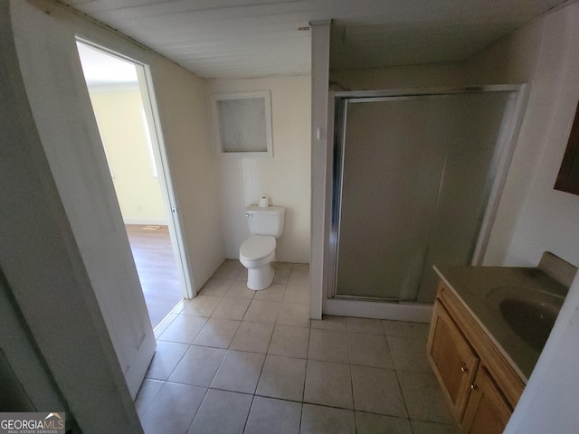 bathroom with a shower with shower door, vanity, tile patterned flooring, and toilet