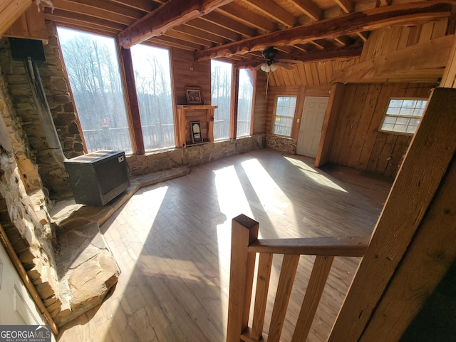 interior space with ceiling fan, wood walls, and hardwood / wood-style floors