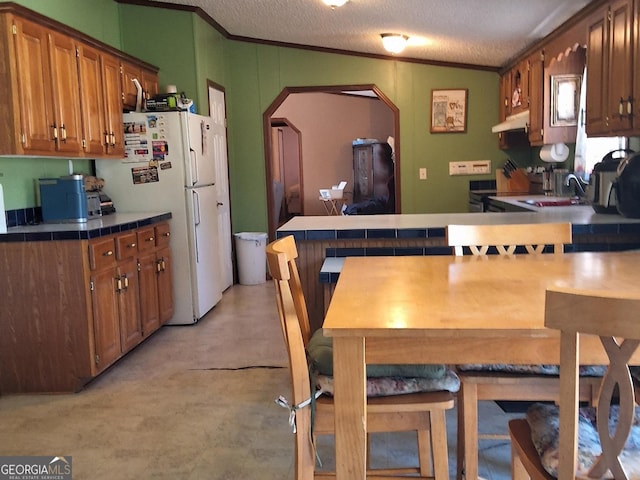 kitchen featuring sink, ornamental molding, a textured ceiling, and white refrigerator