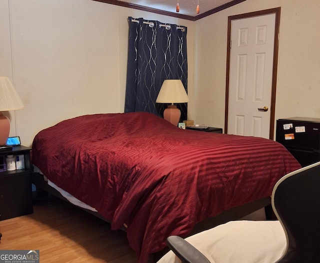 bedroom with wood-type flooring and ornamental molding