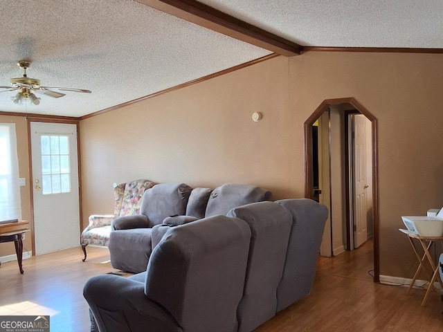 living room with hardwood / wood-style flooring, ceiling fan, lofted ceiling with beams, and a textured ceiling