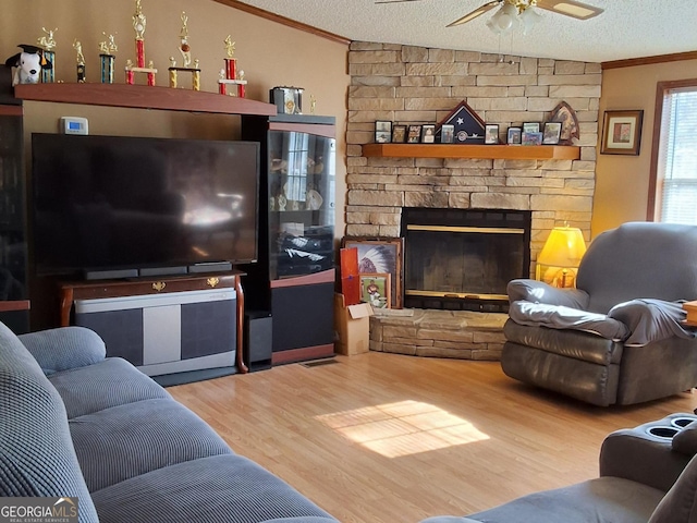 living room with hardwood / wood-style flooring, a stone fireplace, a textured ceiling, and vaulted ceiling