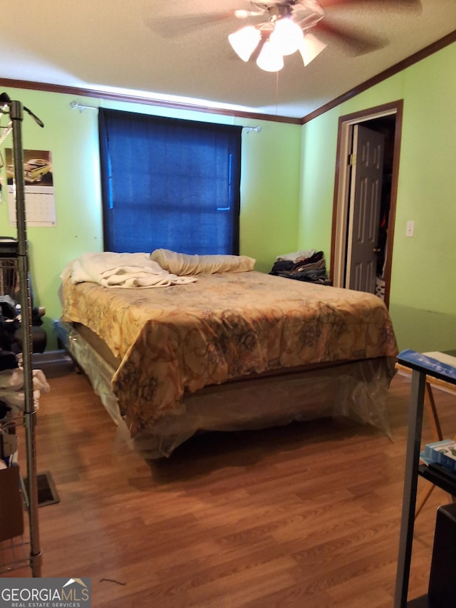 bedroom featuring ceiling fan, ornamental molding, a textured ceiling, and hardwood / wood-style flooring