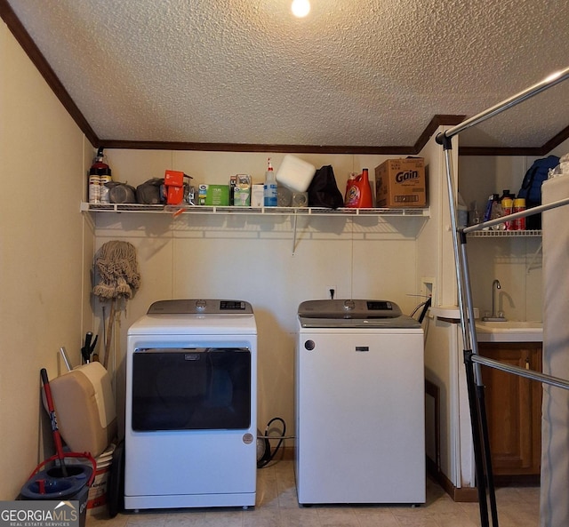 laundry area with a textured ceiling, washer and dryer, and crown molding