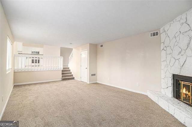 unfurnished living room featuring carpet and a stone fireplace