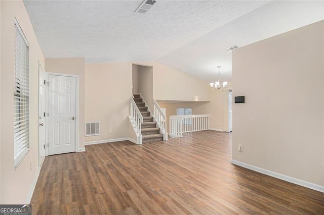 interior space featuring a notable chandelier, dark hardwood / wood-style floors, lofted ceiling, and a textured ceiling