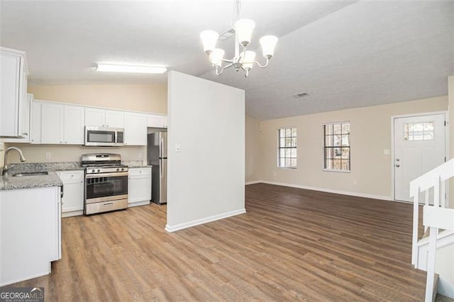 kitchen with sink, stainless steel appliances, a notable chandelier, pendant lighting, and white cabinets