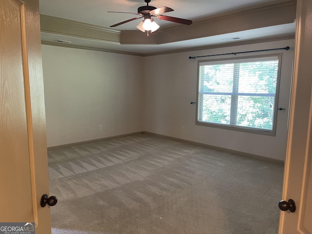 empty room featuring light carpet, a raised ceiling, ceiling fan, and crown molding