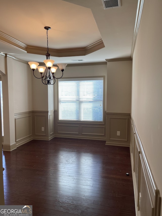 unfurnished room with a tray ceiling, crown molding, dark wood-type flooring, and an inviting chandelier