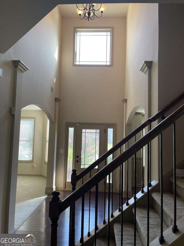 staircase featuring hardwood / wood-style floors, a towering ceiling, and a chandelier