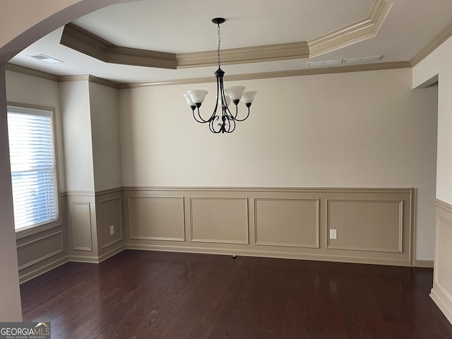 unfurnished dining area featuring crown molding, a raised ceiling, dark wood-type flooring, and a chandelier