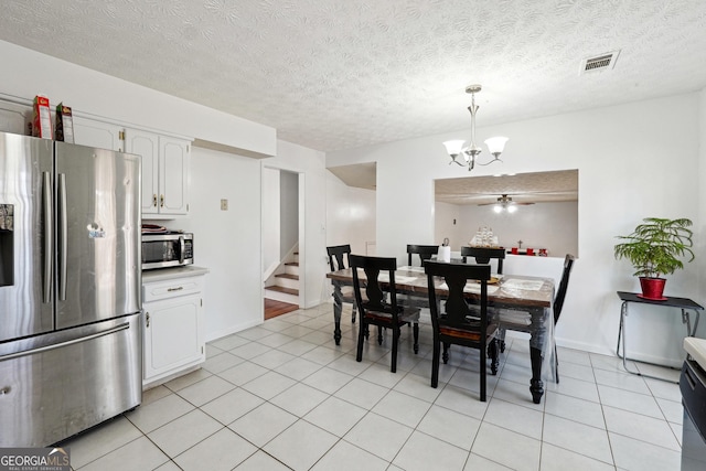 dining room featuring ceiling fan with notable chandelier, light tile patterned floors, and a textured ceiling