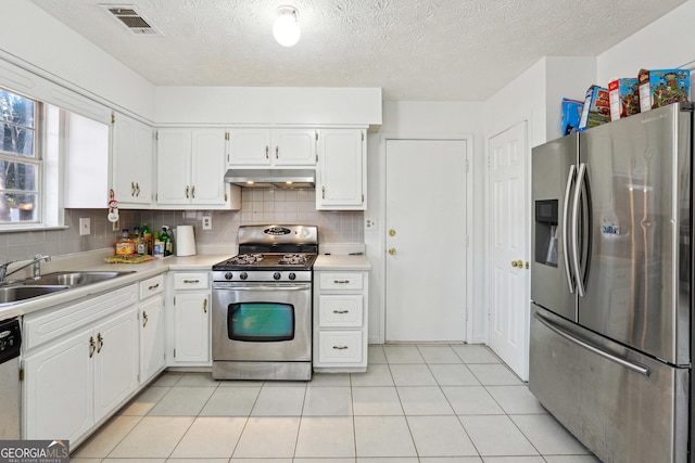 kitchen featuring backsplash, white cabinets, sink, light tile patterned floors, and appliances with stainless steel finishes