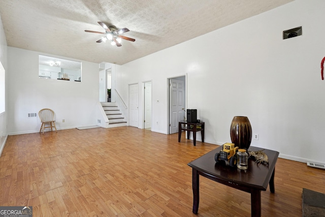 living room featuring ceiling fan, wood-type flooring, and a textured ceiling