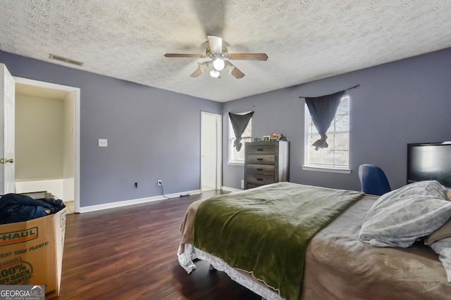 bedroom featuring ceiling fan, dark hardwood / wood-style flooring, and a textured ceiling