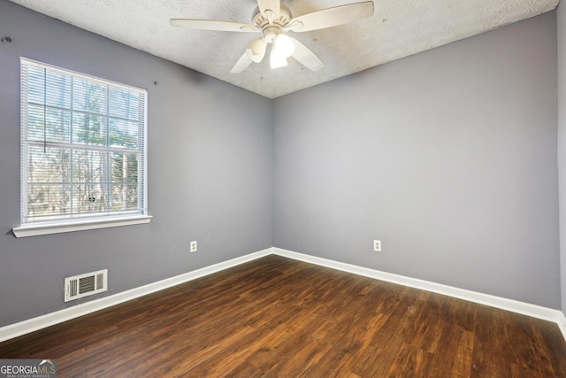 spare room with a textured ceiling, ceiling fan, and dark wood-type flooring