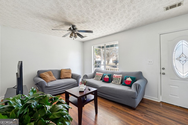 living room with ceiling fan, dark wood-type flooring, and a textured ceiling