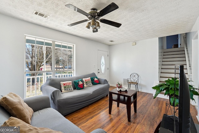 living room with ceiling fan, dark hardwood / wood-style flooring, and a textured ceiling