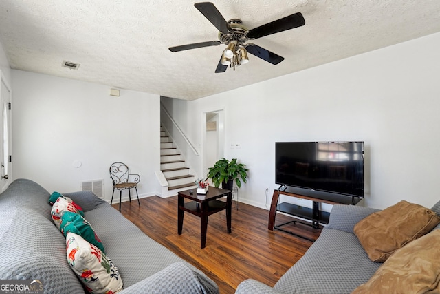 living room featuring ceiling fan, dark wood-type flooring, and a textured ceiling