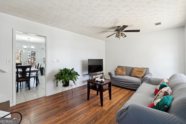 living room with hardwood / wood-style floors, ceiling fan with notable chandelier, and a textured ceiling