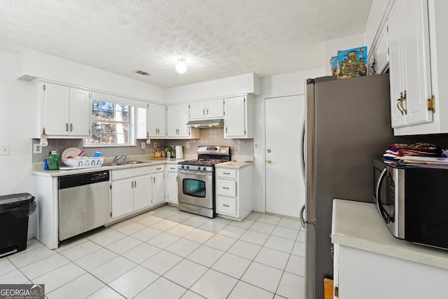 kitchen featuring appliances with stainless steel finishes, backsplash, a textured ceiling, sink, and white cabinets