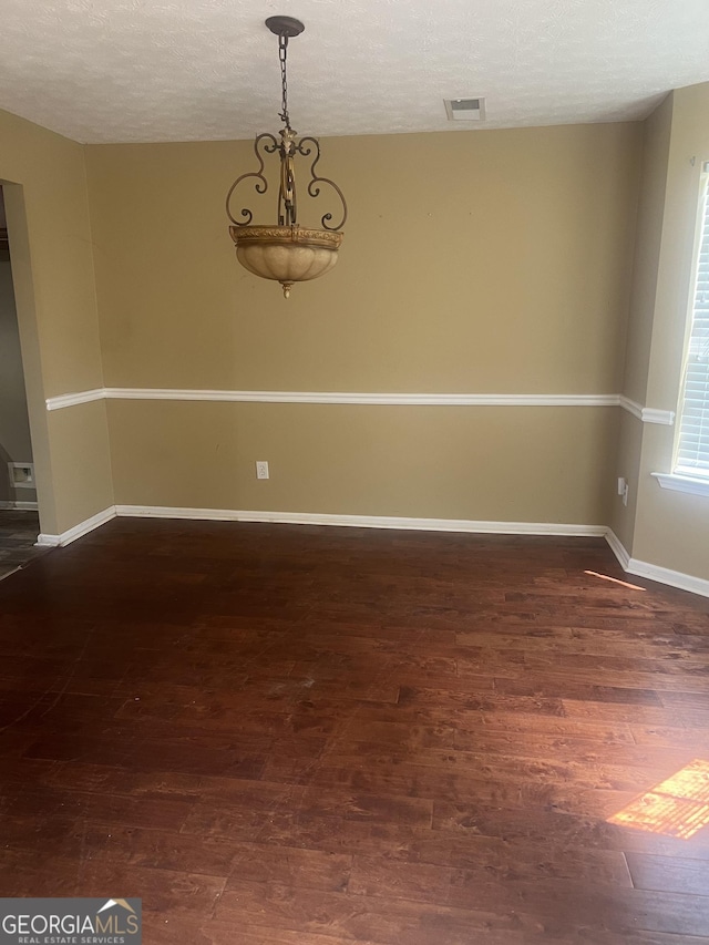 spare room with a textured ceiling and dark hardwood / wood-style floors